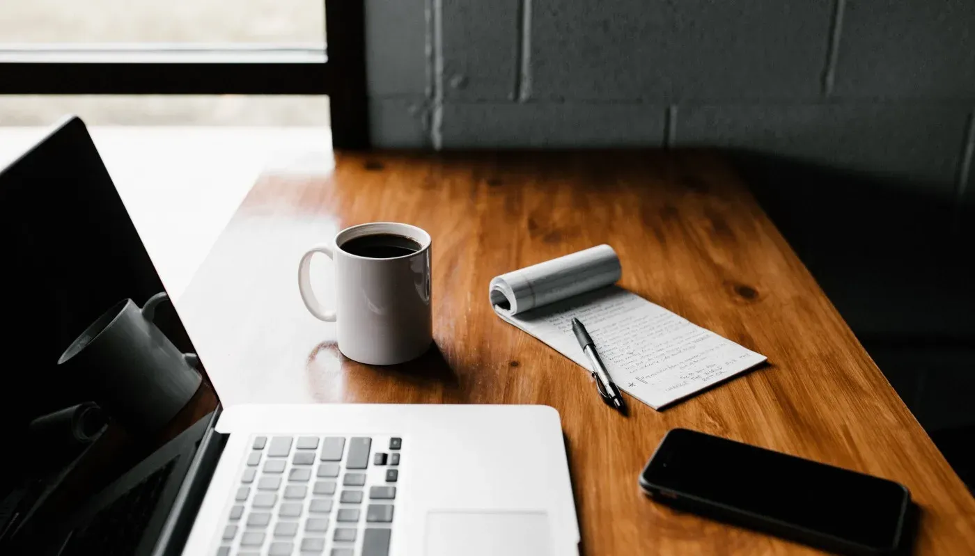 photo of laptop, coffee, notepad and phone