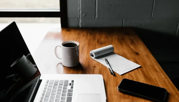 photo of laptop, coffee, notepad and phone